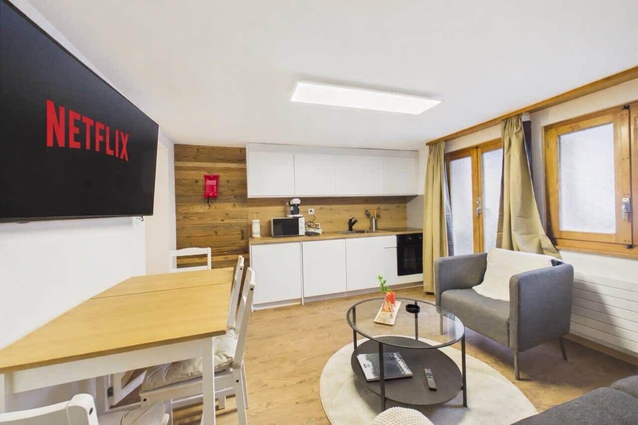 Una habitación moderna con cocina, comedor y zona de estar con sofá y mesa de centro.