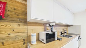 Une cuisine équipée d’un four à micro-ondes, d’un évier et de meubles de rangement en bois.