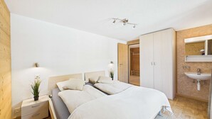 Ein Schlafzimmer mit Bett, Nachttischen, einem Spiegel und einem Badezimmer mit Waschbecken.
