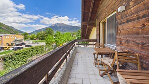 Un balcon en bois offrant une vue sur les montagnes, avec une table et des chaises.