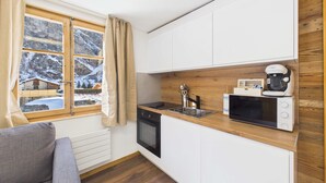 A compact kitchen with a window, wooden cabinets, a microwave, and a dishwasher.