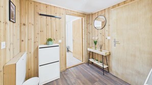 A wooden-paneled room with a white cabinet, a mirror, and a door leading to another room.