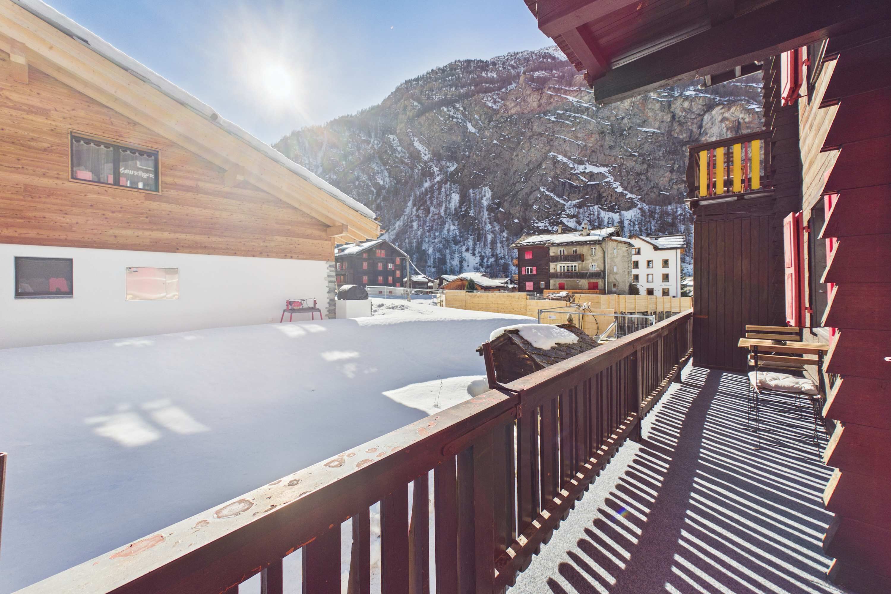 A wooden building with a balcony overlooking a snowy mountain.