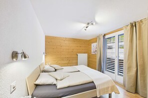 Una camera da letto con testiera in legno, un letto con cuscini, una lampada a parete e una finestra con tende.