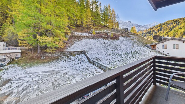 Un balcon offrant une vue sur un paysage enneigé, des arbres et une montagne en arrière-plan.