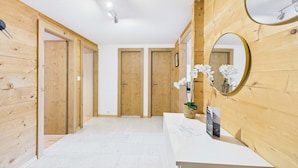 Un couloir aux murs en bois, un comptoir d’accueil blanc et deux portes en bois.