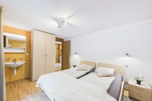 Quarto com cama, mesas de cabeceira, luminária, espelho e guarda-roupa de madeira.