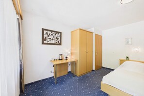 Habitación de hotel con cama, escritorio, armario y una obra de arte colgada en la pared.