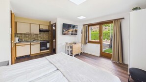 Una habitación compacta con cama, kitchenette, comedor y ventana con cortinas.