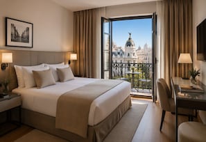 A hotel room with a large bed, a desk with a chair, a balcony with a view of a cityscape, and a framed picture on the wall. - Hotel Mar Salada (Barajas)