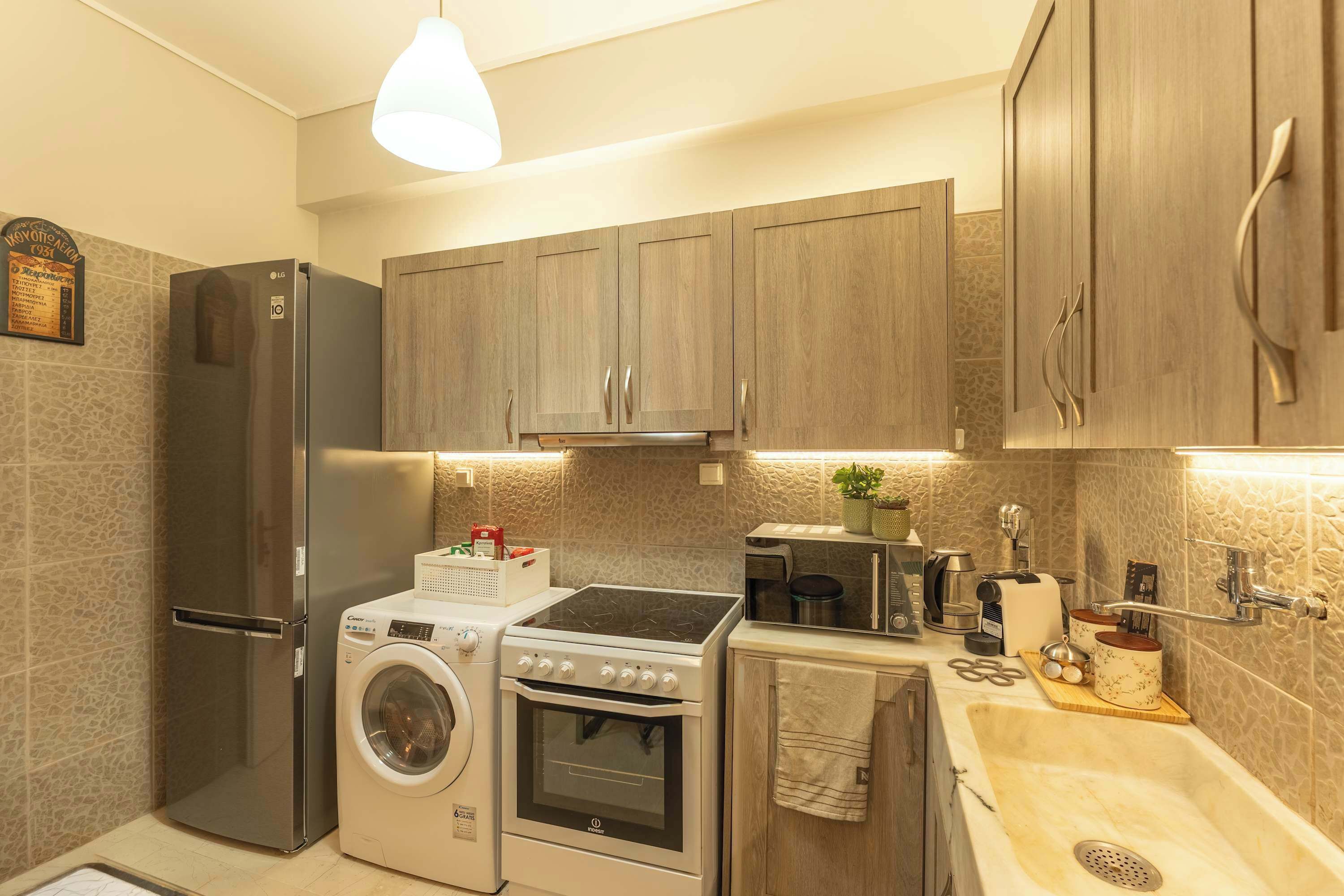 Una cocina compacta con refrigerador, lavadora, estufa y pileta.