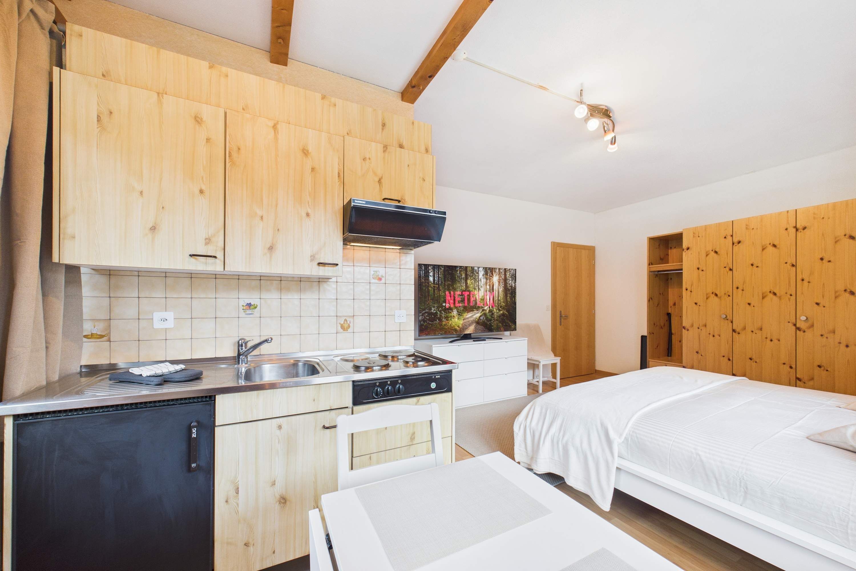A compact kitchen with wooden cabinets, a stove, and a sink.