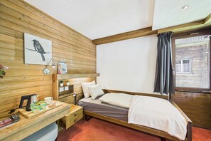 A wooden-paneled room with a bed, a desk with a kettle, a cup, and a picture frame. - Central Studio with Mountain Views in Saas-Fee (Saas-Fee)