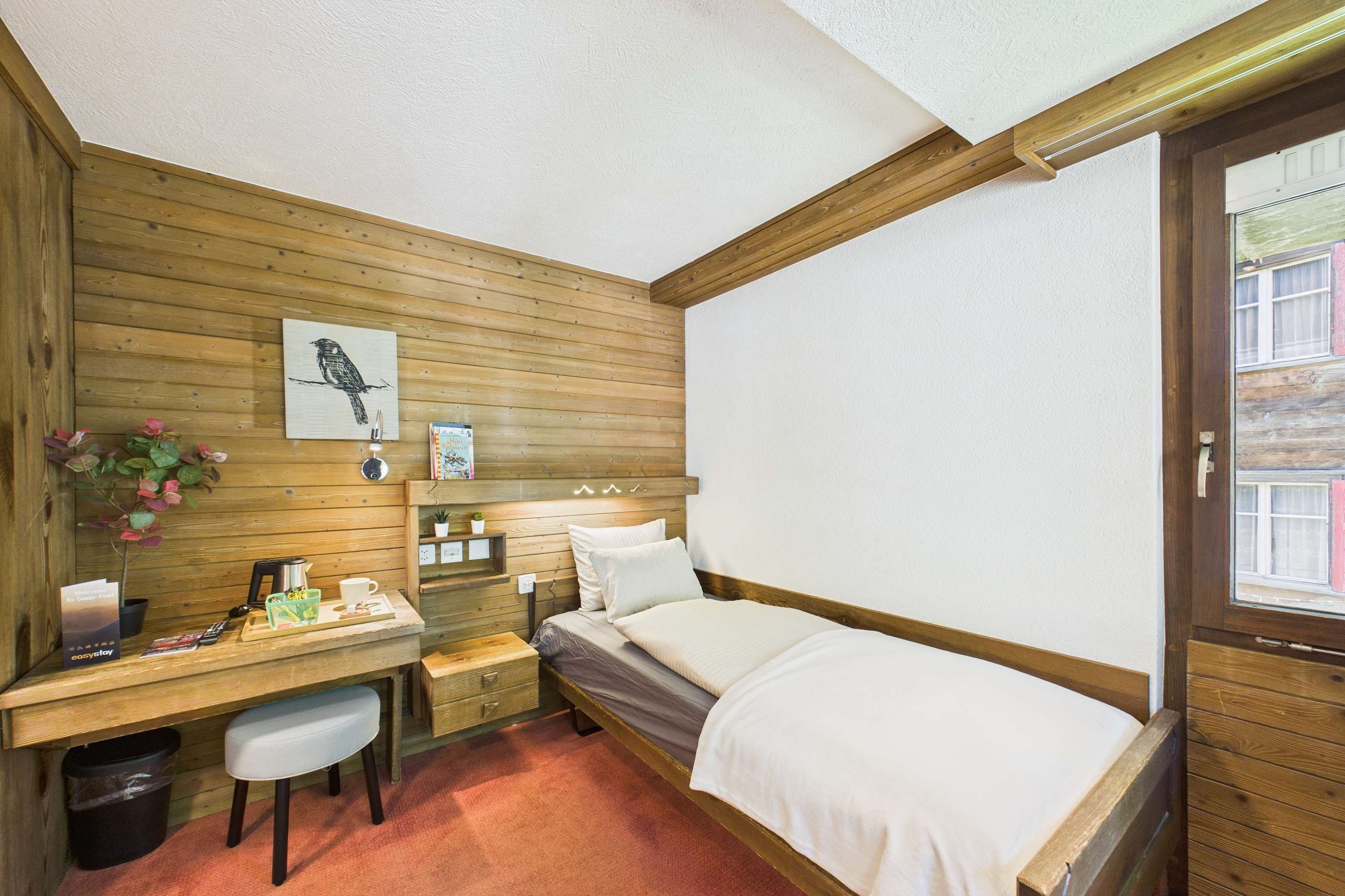 Ein Zimmer mit Holzwänden, einem Bett, einem Schreibtisch und einem Stuhl.