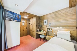 Une chambre à coucher avec une tête de lit en bois, un bureau, une chaise, un lit et un téléviseur fixé au mur.