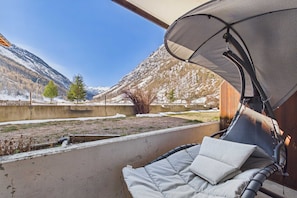 A balcony with a cushioned chair, a view of mountains, and a clear sky. - Charming Täsch Apartment, 500m to Zermatt Train (Täsch)