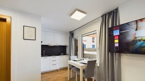 Ein modernes Zimmer mit Esstisch, Fernseher und Blick ins Freie.