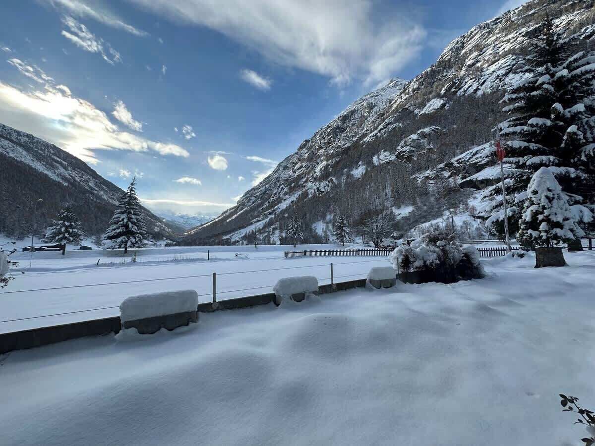 Un paysage enneigé avec une montagne, une clôture et quelques arbres.