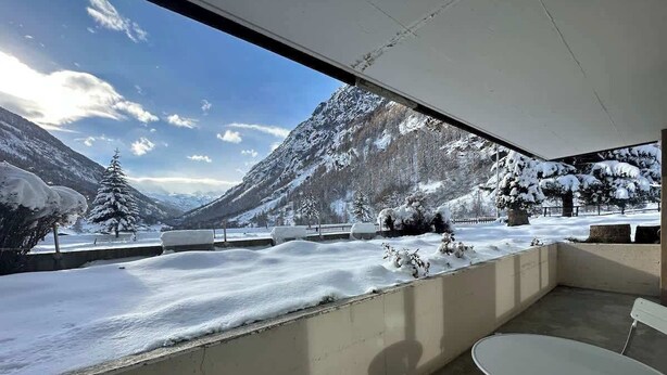 Ein Balkon mit Blick auf verschneite Berge und einen klaren Himmel.