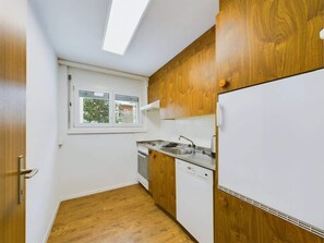Une cuisine compacte dotée d’un puits de lumière, de meubles en bois, d’une cuisinière et d’un lave-vaisselle.