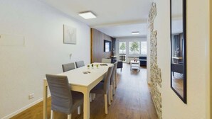Una habitación amplia con una larga mesa de comedor, sillas, un televisor y una pared decorativa de piedra.
