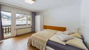 Un dormitorio con cama, ventana, radiador y puerta.