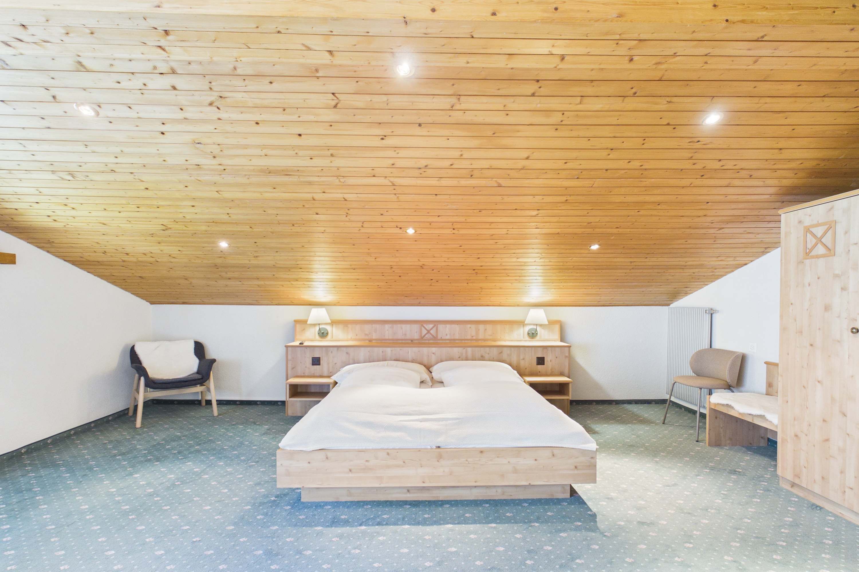Une chambre à coucher avec un plafond en bois, un lit, deux tables de chevet et deux chaises.