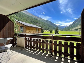 A wooden cabin with a balcony overlooking a mountainous landscape.