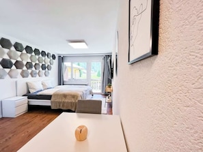 A modern bedroom with a bed, bedside table, and a wall-mounted geometric pattern.