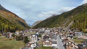 Un pueblo de montaña con edificios de estilo chalete, una carretera principal y un valle.
