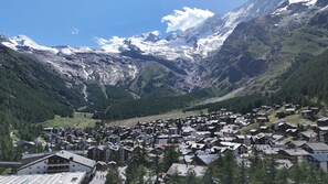 Un village de montagne aux maisons traditionnelles, une vallée et des sommets enneigés.
