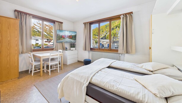 Un dormitorio con cama, escritorio y ventana con vista a la montaña.