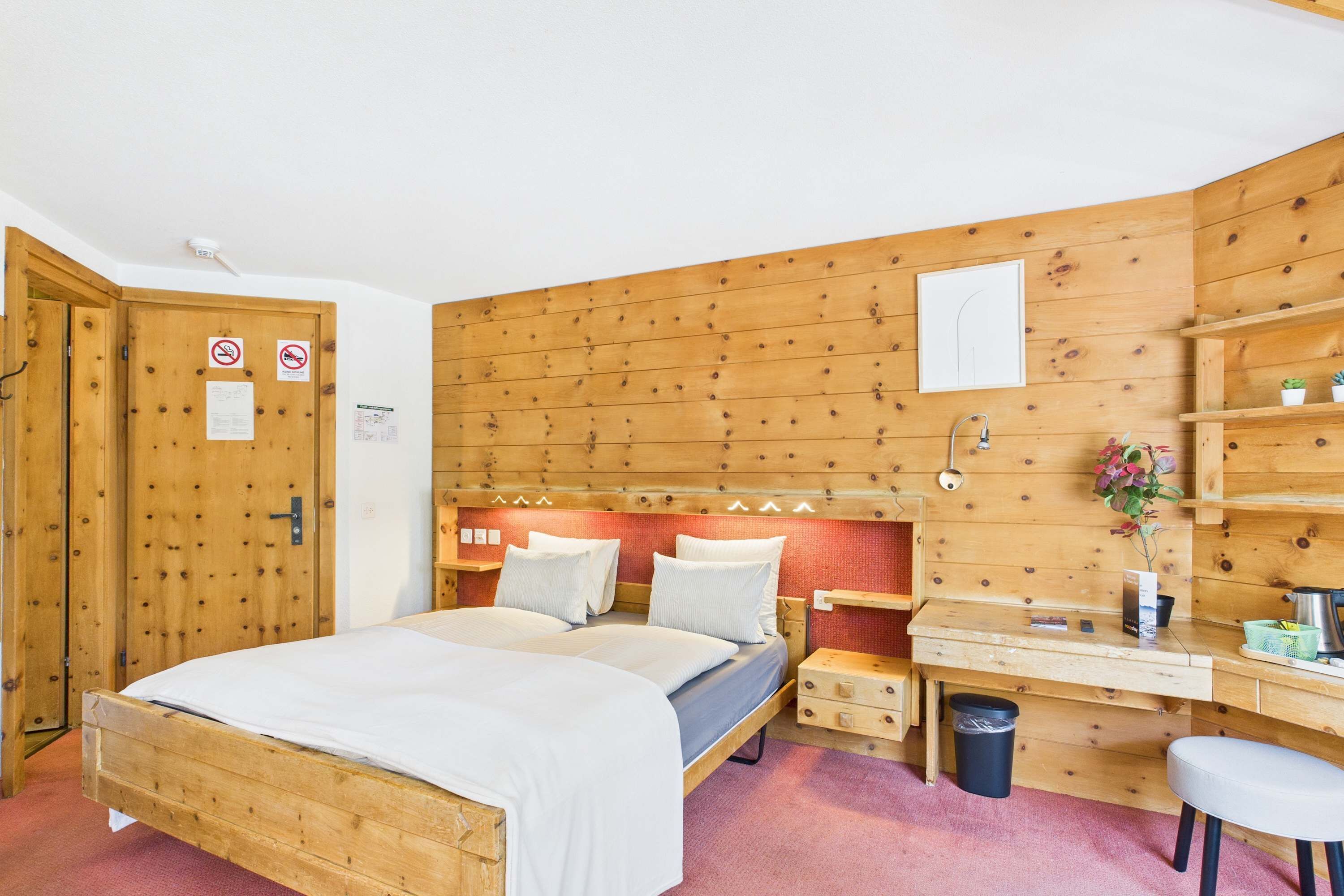 A wooden-paneled room with a bed, a desk, and a chair.