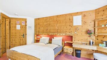 A wooden-paneled room with a bed, a desk, and a chair.