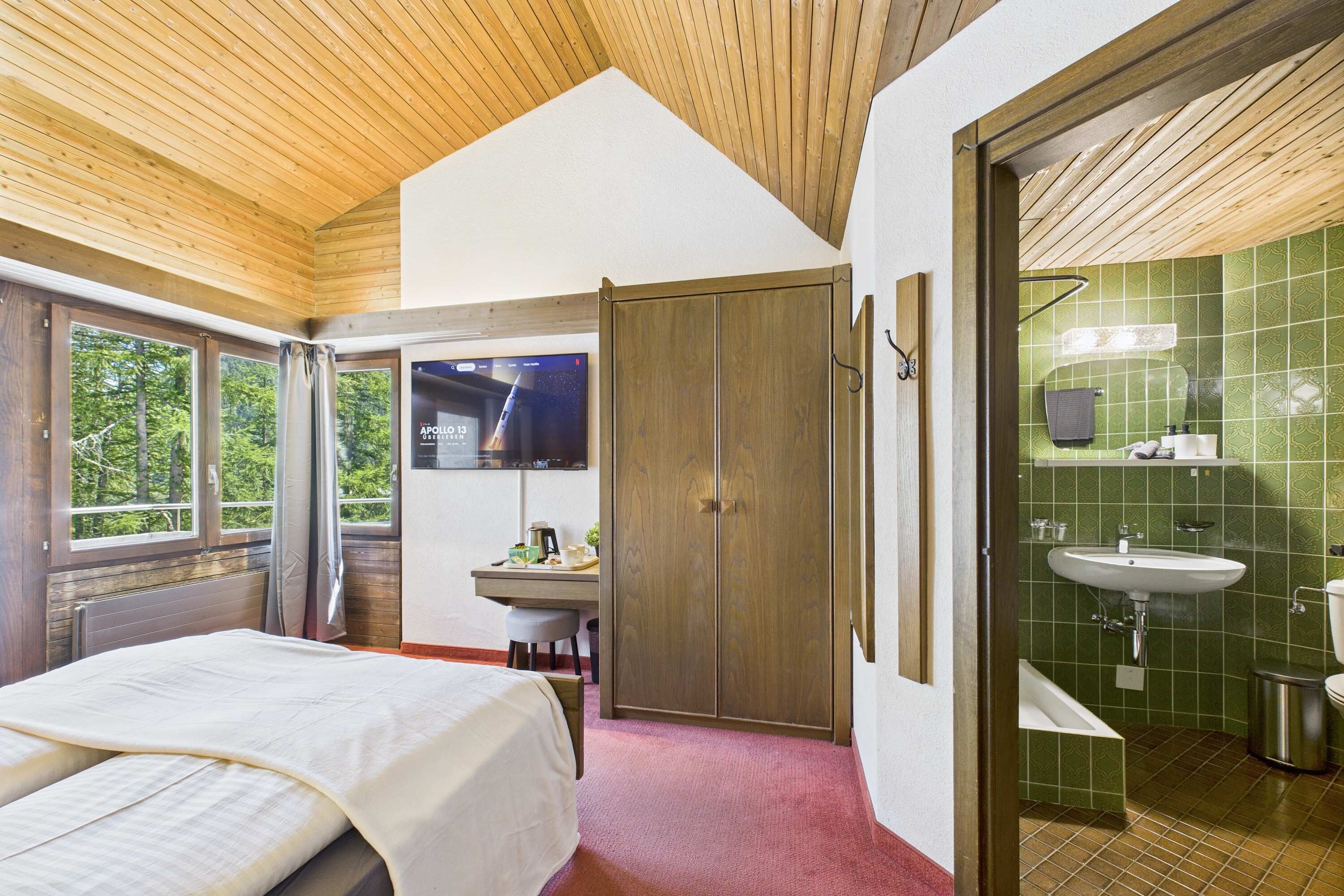 Un dormitorio con cama, escritorio, televisor y armario.