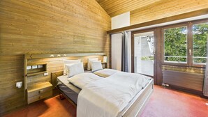 Un dormitorio con paneles de madera, una cama, mesitas de noche y una ventana.