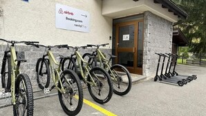 A building with a sign for Airbnb, a bike rack with bicycles, and a door with a sign. - Mountain View Apartment Steps from Zermatt (Täsch)