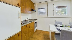 A compact kitchen with a sink, stove, and window. - Mountain View Apartment Steps from Zermatt (Täsch)