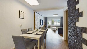 Un comedor con una mesa larga, sillas y un televisor montado en la pared.