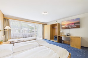 Una habitación de hotel con dos camas, un escritorio, una silla, un televisor y un armario.