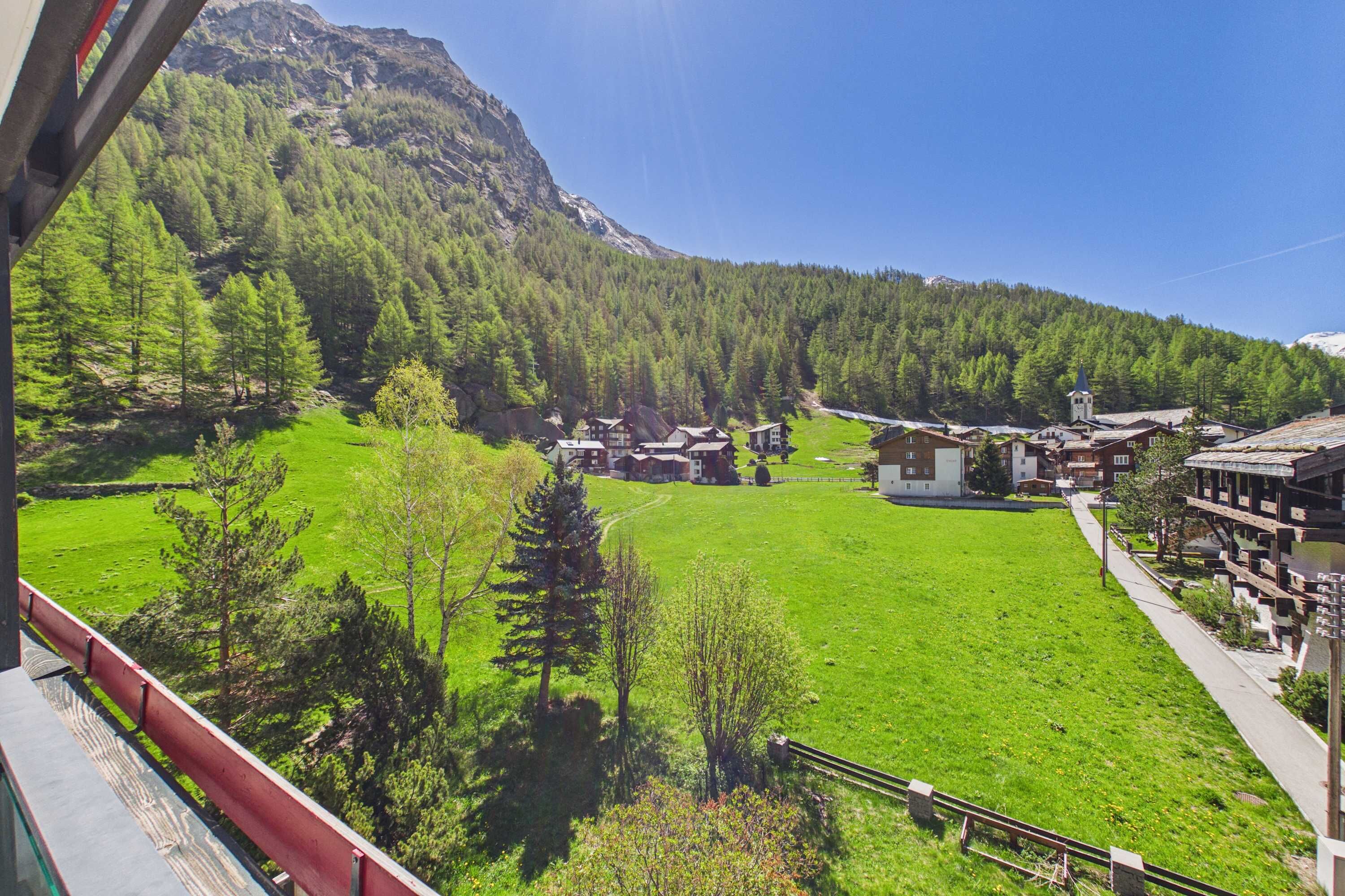 Eine Berglandschaft mit einem grünen Feld, Gebäuden und einer Kirche.