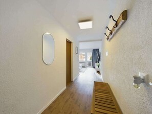 Ein Flur mit einer Holzbank, einem runden Spiegel und einer Wandleuchte.