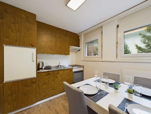 Une cuisine compacte avec des meubles en bois, une cuisinière intégrée et un coin repas avec une table dressée pour deux personnes.