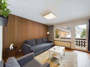 Ein modernes Wohnzimmer mit einer Couch, einem Couchtisch und einer Topfpflanze.
