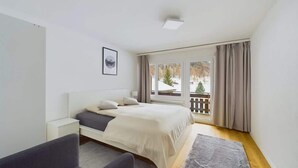 Une chambre à coucher avec un lit, une table de chevet et une vue sur un balcon.