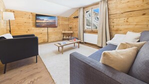 Tunnelmallinen huone, jossa on puuseinät, sohva, sohvapöytä ja taulu.