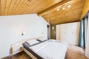 A bedroom with a wooden ceiling, a bed with white bedding, a bedside table, and a wardrobe. - Central Apartment for 6 the Heart of Saas-Fee (Saas-Fee)