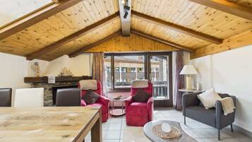 Une pièce chaleureuse avec un plafond en bois, une cheminée, une table à manger et deux canapés.