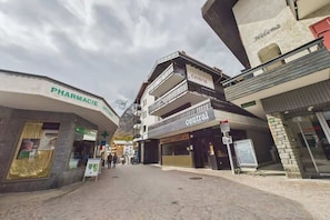 A street with buildings, including a pharmacy and a central building with balconies. - Central Apartment for 6 the Heart of Saas-Fee (Saas-Fee)