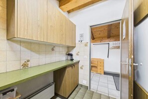 Une petite cuisine avec des meubles en bois, un plan de travail vert et un pare-feu en carreaux.